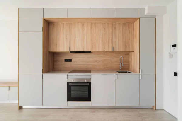 Cocina contemporánea mínima en apartamento reformado vacío. Mobiliario de madera y electrodomésticos modernos —  Fotos de Stock