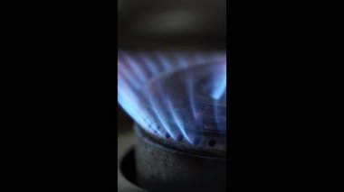 Mutfak ocağının ateşine yakın çekim. Ocakta yanan gaz alevi. Dikey görüntüler.
