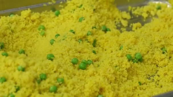 Mencampur couscous matang dengan kacang polong hijau di nampan logam. Proses memasak di dapur komersial. — Stok Video