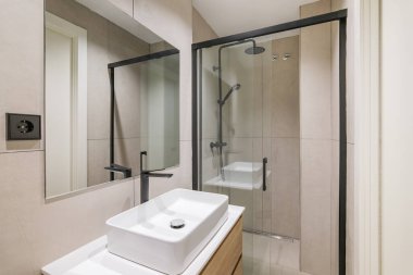 Yenilenmiş dairede modern tarz banyo. Duş alanı, siyah musluk ve aynayla batmak..