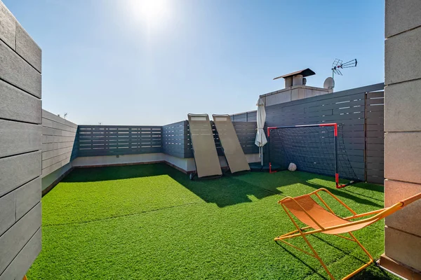 Privé terras met ligbedden, kindervoetbalhekken en kunstgras op zonnige dag met blauwe lucht. Rechtenvrije Stockfoto's
