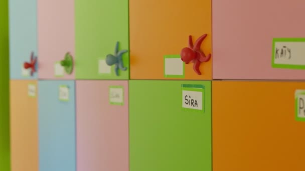 Placas con nombres para niños en casilleros preescolares. Cambio de enfoque de puertas de colores con nombres de niños. — Vídeos de Stock