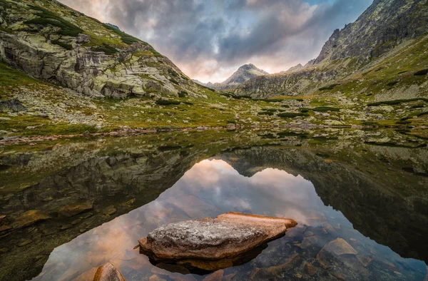 Horské jezero s kameny v popředí při západu slunce — Stock fotografie