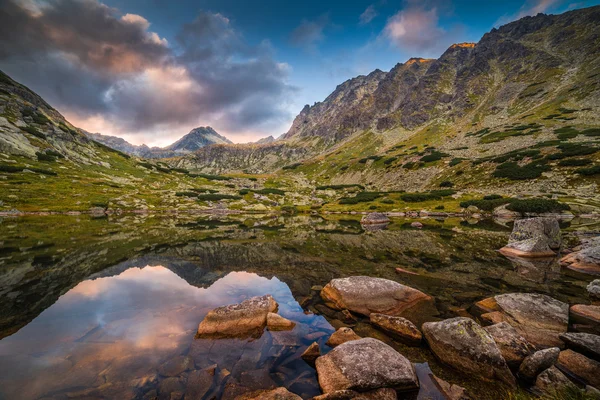 Bergsee mit Felsen im Vordergrund bei Sonnenuntergang — Stockfoto