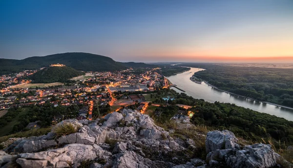 Upplysta små staden med floden från kullen vid solnedgången — Stockfoto