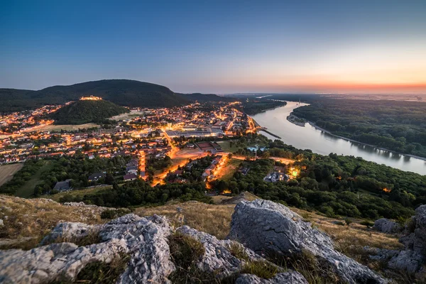 Pohled na osvětlené malé město s řekou z kopce při západu slunce — Stock fotografie