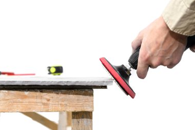 Bir adam seramik fayansı zımpara makinesiyle öğütüyor.