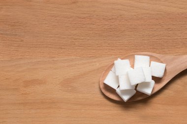 Tahta arka planda kaşıkta şeker ve metin için bir yer.