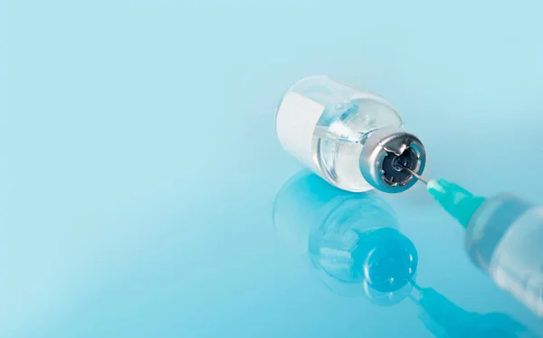 Tıbbi arka plan şırıngası mavi yansıtıcı tıbbi bir masaya enjekte edilecek. Nüfusun Coronavirus Covid-19 'a karşı aşılanması. Metin için yer.