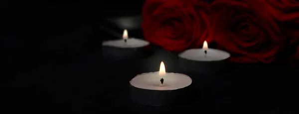 The concept of mourning, mourning, death from disease, funeral. Banner with burning candles and ribbon on a black background. Copy space. space for text