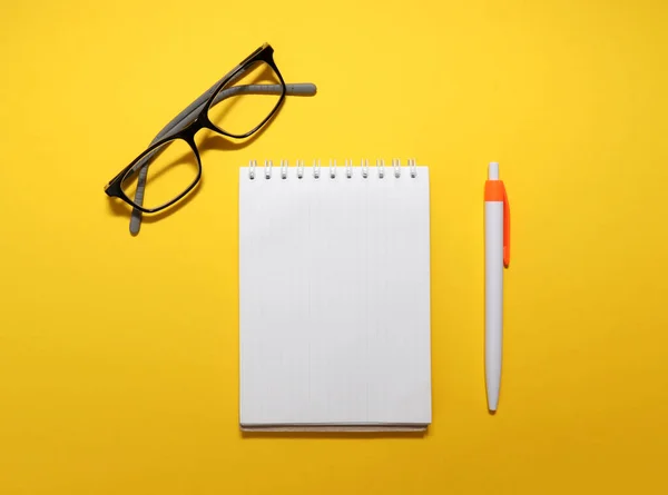 Vista Superior Dos Óculos Bloco Notas Caneta Sobre Fundo Amarelo — Fotografia de Stock