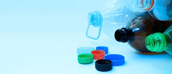 Plastic bottles and lids on a light background with space for text., copy space. The concept of separate sorting of plastic, rejection of plastic, production of plastic bottles.