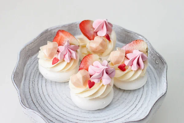 Mini-Pavlova-Kuchen mit Schokoladenherzen, frischen Erdbeeren und roten herzförmigen Streusel — Stockfoto