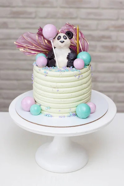 Hermoso pastel de cumpleaños verde con figura de oso panda, bolas de chocolate y espolvoreos. Imágenes de stock libres de derechos