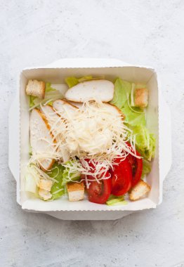 Sezar salatası paket olarak paket olarak servis edilecek. Tarafsız gri arka planda.