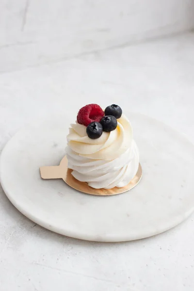Tarta de bayas Pavlova con arándanos, frambuesas y crema batida de vainilla sobre un fondo de mármol —  Fotos de Stock