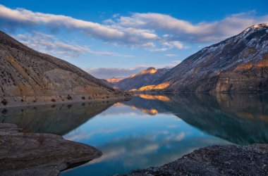 Tortum Gölü, Doğu Türkiye. Gün batımında Tortum Gölü 'nün yüzeyinde güzel bir yansıma. Gizemli renk ve atmosfer. Tortum, Erzurum, Türkiye. Ocak 2021