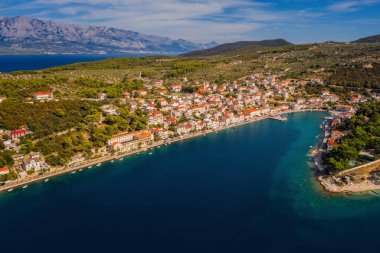 POVLJA, CROATIA - Ağustos 2020: Brac Adası 'ndaki güzel Povlja köyü ve arkaplanı Mosor dağı. Panoramik manzara. Hava aracı görüntüsü.