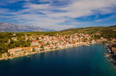 POVLJA, CROATIA - Ağustos 2020: Brac Adası 'ndaki güzel Povlja köyü ve arkaplanı Mosor dağı. Panoramik manzara. Hava aracı görüntüsü.