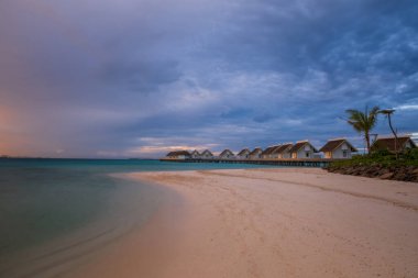 Okyanusta bir ada, gün batımında deniz aşırı villalar. Maldivler kavşağı, Hard Rock Oteli. Temmuz 2021. Uzun pozlama resmi