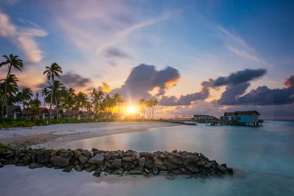 Palmeras en la costa tropical al atardecer. Crossroads Maldives, hard rock hotel, junio 2021. Imagen de larga exposición — Foto de Stock