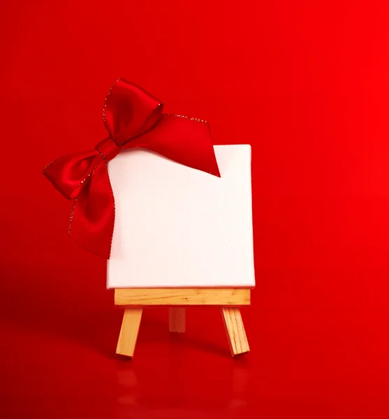 Trä staffli med tom duk på jul röd bakgrund — Stockfoto