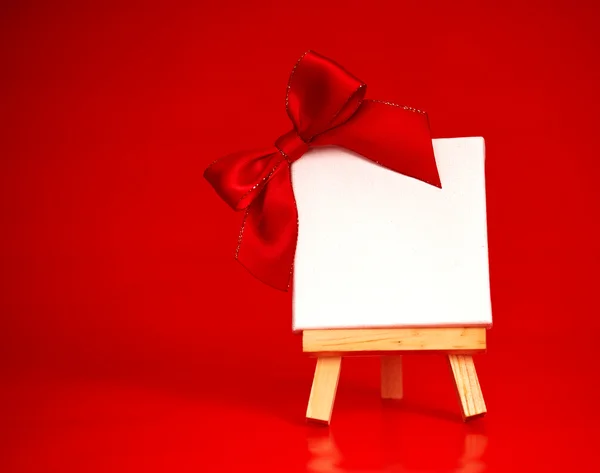 Caballete de madera con lienzo en blanco sobre fondo rojo navidad —  Fotos de Stock