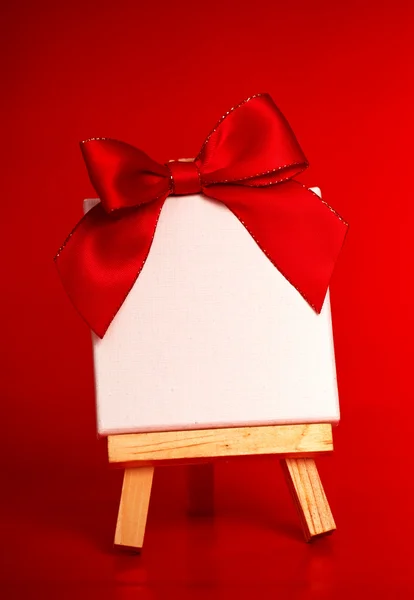 Caballete de madera con lienzo en blanco sobre fondo rojo navidad —  Fotos de Stock