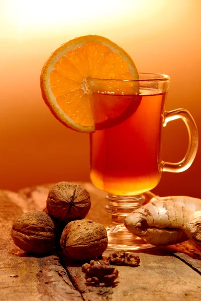 Orange, Walnüsse, Ingwer und eine Tasse Tee auf einem Holztisch auf der Stirn — Stockfoto