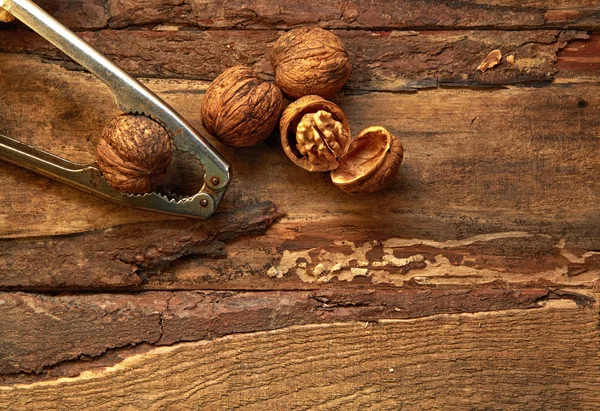 Walnuts and nutcracker on wooden background — Stock Photo, Image