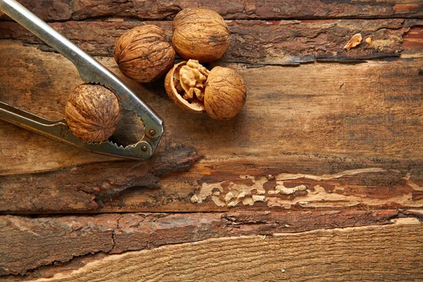 Ořechy a louskáček na dřevěném pozadí — Stock fotografie