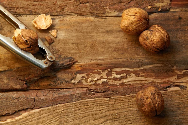 Walnuts and nutcracker on wooden background — Stock Photo, Image