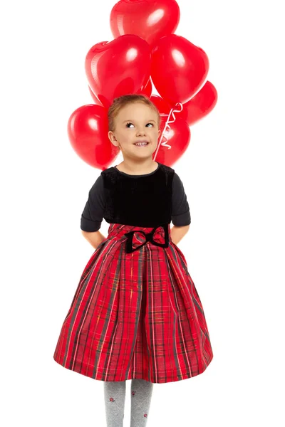 Linda niña sosteniendo un montón de globos rojos en forma de corazón —  Fotos de Stock