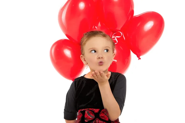 Cute little girl holding a bunch of red heart-shaped balloons — Stock Photo, Image