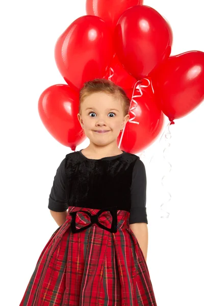 Menina bonito segurando um monte de balões em forma de coração vermelho — Fotografia de Stock