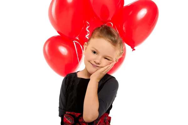 Милая маленькая девочка с кучей красных шаров в форме сердца — стоковое фото