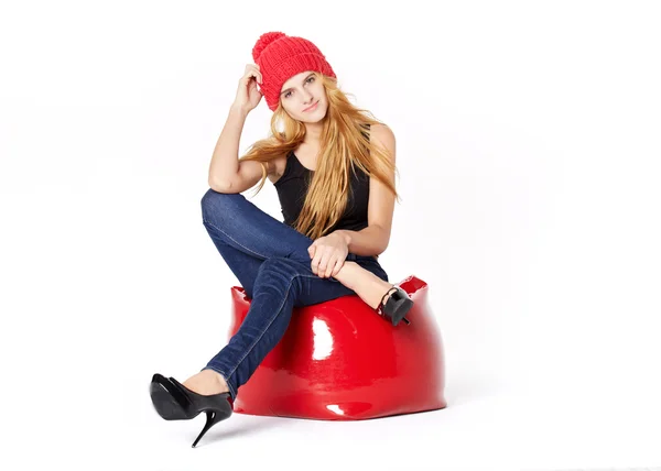 Krásná mladá žena, sedící na židli červené v červené čepici. Valen — Stock fotografie