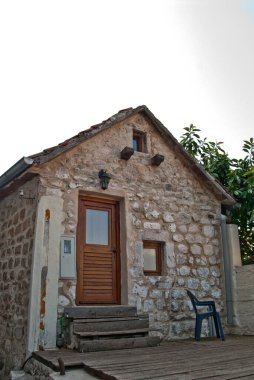 Kahverengi ahşap kapılı küçük taş ev.