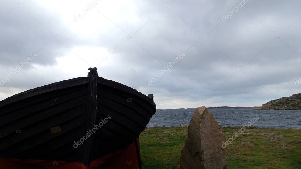 A wooden boat on the ocean coast in southern Sweden with a cloudy sky