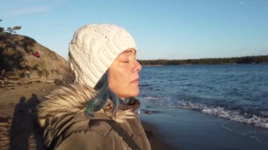 Gün batımında deniz kenarında genç bir kadını temsil eden 4K 'de kısa bir video.