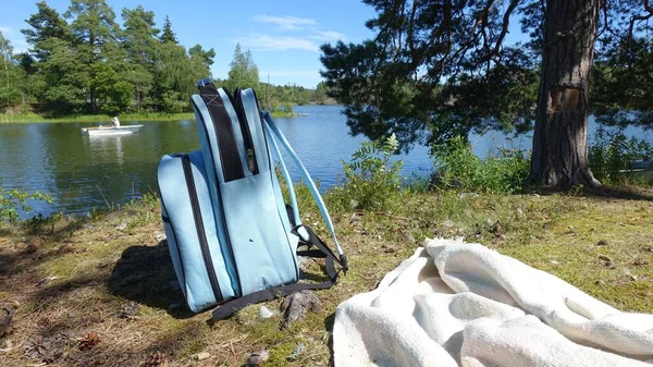 Niebieski plecak i koc na brzegu jeziora.. — Zdjęcie stockowe