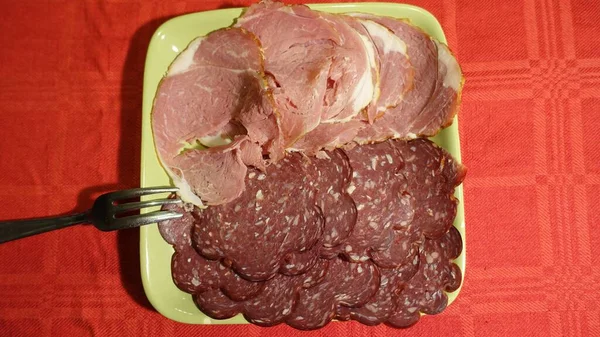 Cortes frios mistos de carne de porco servida em uma placa verde — Fotografia de Stock