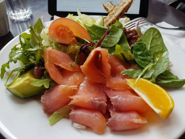 Avokado, ıspanak, roket, siyah zeytin ve domatesli somon salatası. Limonla kaplanmış..