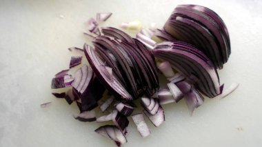 Taze kesilmiş kırmızı soğan, yağlı bir tavaya konmaya hazır.