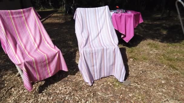 Видео, как два пляжных полотенца высыхают на стульях и стол, на котором больше полотенец и маски для дайвинга — стоковое видео