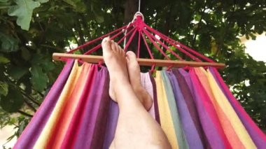 Renkli bir hamakta sallanan bir insan ayağı videosu