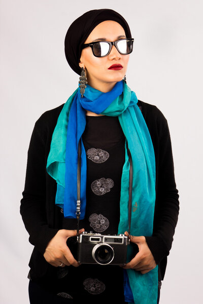 Young Woman holding old camera in hijab and colourful scarf