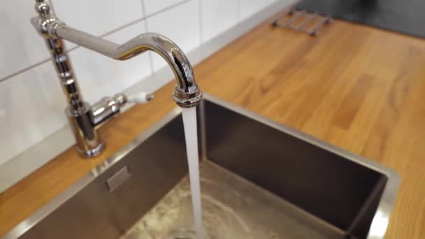 Machos mano verter agua en el vaso de cromo grifo para beber agua corriente con burbujas de aire. agua potable y segura para beber. hombre llenando un vaso de agua de un grifo de cocina de acero inoxidable. — Vídeos de Stock