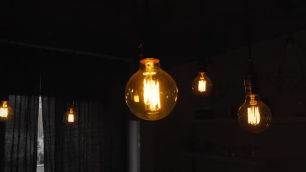 Великі старовинні лампочки розжарювання висять на темній кухні. Декоративні антикварні лампочки з прямим дротом. Недостатня нитка лампочок витрачає електроенергію. Теплий білий тьмяний, світлодіодний — стокове відео