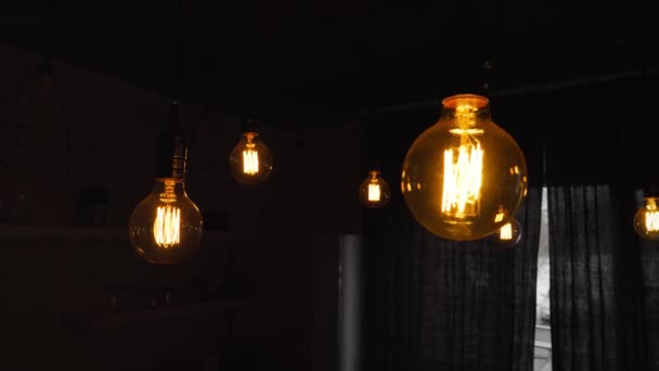 Big vintage incandescent light bulbs hanging in the dark kitchen. Decorative antique edison light bulbs with straight wire. Inefficient filament light bulbs waste electricity. Warm white dimmable, led — стоковое видео